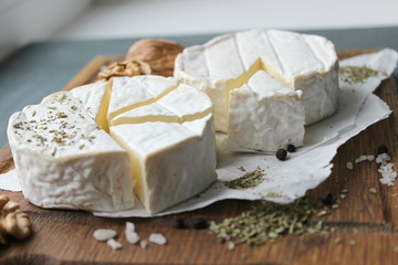 Camembert cheese. Farm products, rustic cheese. Natural cheese, round head of cheese with Camembert mold, cut on a wooden Board surrounded by fragrant spices. Cheese plate for gourmets.
