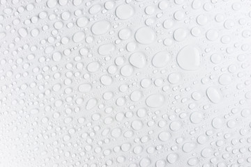 Droplets of water on a white, matte background illuminated with a delicate light.