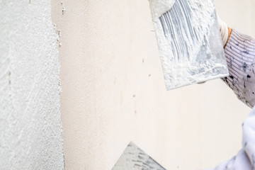 Construction worker plastering and smoothing concrete wall with cement