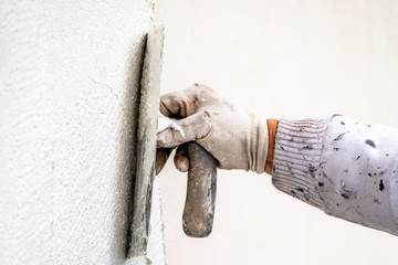 Construction worker plastering and smoothing concrete wall with cement