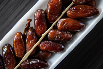 Dried dates in white styrofoam packaging on black wooden table