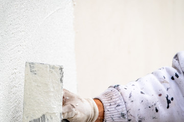 Construction worker plastering and smoothing concrete wall with cement