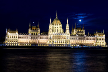 Fototapeta na wymiar View of the Budapest Parliament at dusk with the Moon on its roofs at the blue hour, Hungary