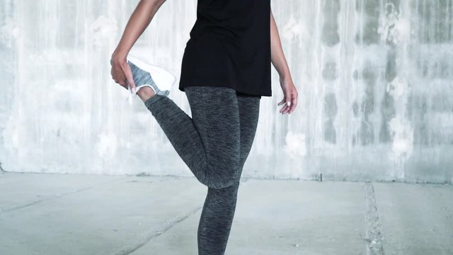 Close up of a young fitness woman stretching hip, hamstring muscles, leg muscles with pigeon pose stretch.