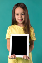 Close-up portrait of cute little child girl holding blank digital tablet on blue background