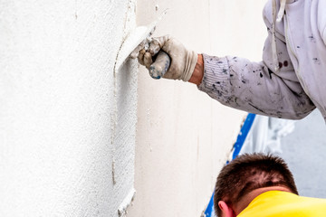 Construction worker plastering and smoothing concrete wall with cement