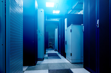 Data center in blue light full of server cabinets and racks