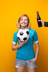 Photo of sports blonde with arms crossed is choosing between ball and bottle of alcohol