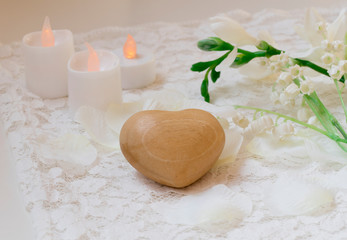close up white romantic scene, wooden heart, candles  and flowers.