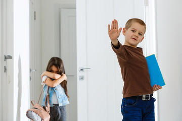School friends bullying a sad girl in corridor at school