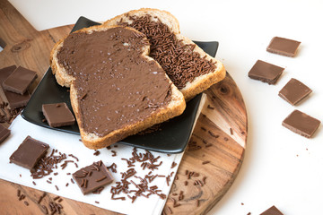 two slices of bread on wooden plate with chocolate paste and hail, Ducht Hagelslag
