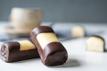 Typical Dutch cake cookie with marzipan and chocolate, called mergpijpje. White table, cup of tea