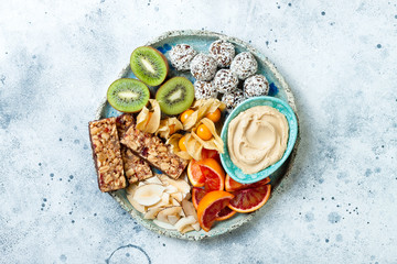 Healthy vegan dessert snacks - protein granola bars, homemade raw energy balls, cashew butter, toasted coconut chips, cape gooseberry, kiwi, blood orange. Concept of healthy sweets for children. - Powered by Adobe