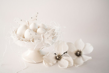 white romantic Easter scene, cake stand with eggs and flowers  against white background, space for text