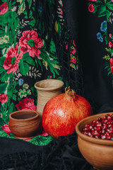 pomegranate grains in a ceramic bowl on a vintage fabric background, pomegranate fruit, ceramic jug, ceramic plate, ethnic shawl, Romma shawl, still life