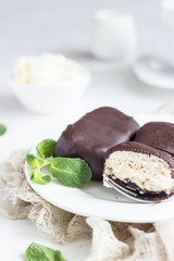 Glazed cheese curds with chocolate and mint on a white plate and a cup of coffee. Sweet breakfast or dessert. High key.