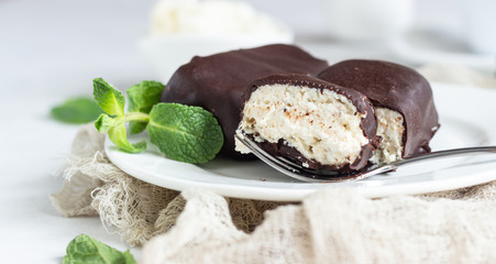 Glazed cheese curds with chocolate and mint on a white plate and a cup of coffee. Sweet breakfast or dessert. High key.