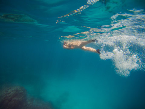young woman swimming and snorkeling with mask and fins in clear blue water