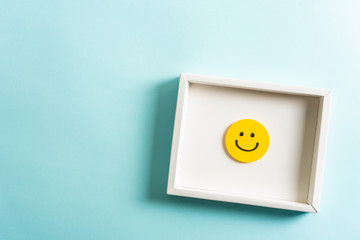 Concept of well done, feedback, employee recognition award. happy yellow smiling cartoon face frame on blue background.