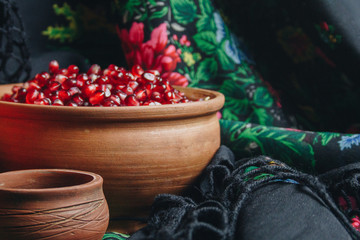 pomegranate grains in a ceramic bowl on a vintage fabric background, pomegranate fruit, ceramic jug, ceramic plate, ethnic shawl, Romma shawl, still life