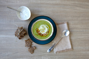 Creamy vegetable soup with kale, cabbage, celery and millet, decorated with olive oil, yoghurt sauce and chilli flakes. Served with seed crackers and lemony yoghurt sauce. Top view.
