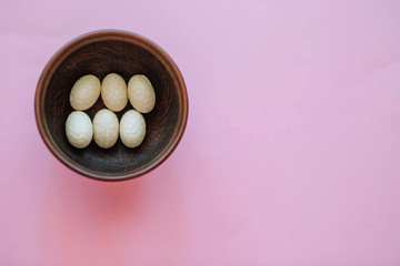 Decorative Easter eggs in a wooden plate on a pink background. Easter concept.