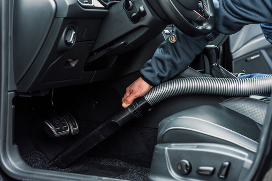 professionelle Autoreinigung in einer Werkstatt - Mann saugt den Innenraum eines Fahrzeuges_professional car cleaning in a garage - man vacuums the interior of a vehicle