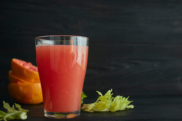 fresh citrus grapefruit juice in a glass. On a black wooden table. Black background. horizontal view. place for text.