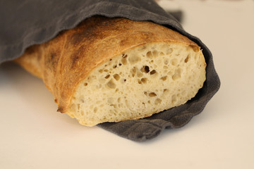 Just baked sourdough loaf - rustic quality homemade wrapped in a napkin. Beautiful picturesque close up image with selective focus on black background.