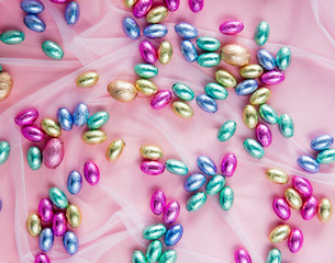 multicolored сhocolate eggs on pink tulle.