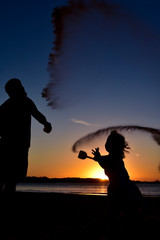 silhouette of a man and a girl on sunset background of blue sky