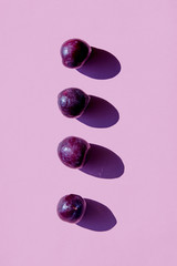 Four plums with shadows on purple background