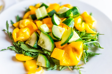 Closeup macro of fresh arugula yellow bell pepper salad on light table in Italy with vegetables lunch or dinner in restaurant