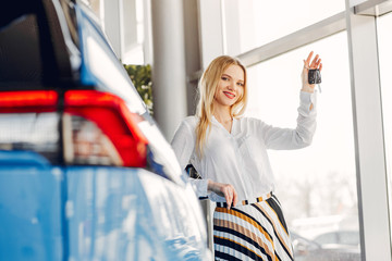 Lady in a car salon. Woman buying the car. Blonde in a white shirt