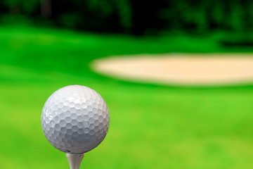 Close up photo of a golf ball in the golf course in a warm sunset light