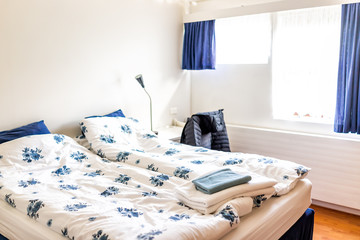 Clean European double queen bed comforter with table lamps and decorative blue pillows in bedroom...