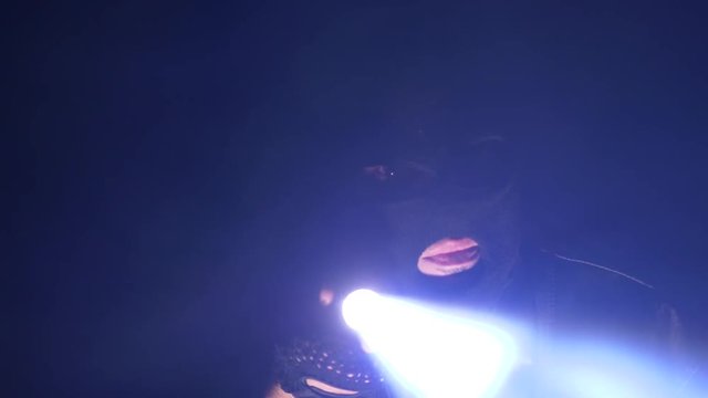 Burglar wearing a mask in the darkness searching with a flashlight.