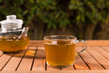 Teapot of green tea on wooden table outdoors