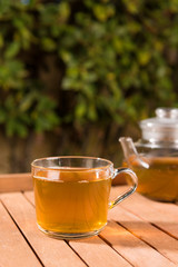 Tasty herbal tea in glass teapot on table, summer leisure