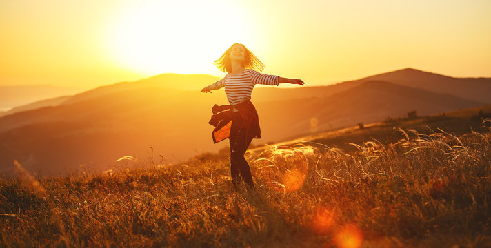 Happy woman jumping and enjoying life  at sunset in mountains.