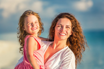 Portrait of happy mother and little daughter on sunny beach on Maldives at summer vacation