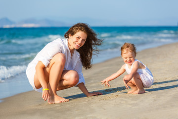 Fototapeta na wymiar Mother and little daughter playing on the sea beach in Greece