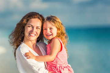 Obraz premium Portrait of happy mother and little daughter on sunny beach on Maldives at summer vacation