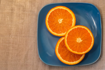 Citrus. A mandarin is served on a blue plate. A half tangerine or an orange on a table. Close-up. Soft focus. Top view. Copy space.