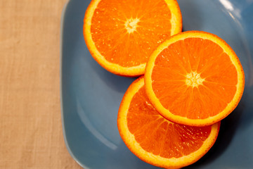 Citrus. A mandarin is served on a blue plate. A half tangerine or an orange on a table. Close-up. Soft focus. Top view. Copy space.