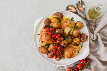 Roasted chicken thighs with baby potatoes, tomatoes, rosemary and onion