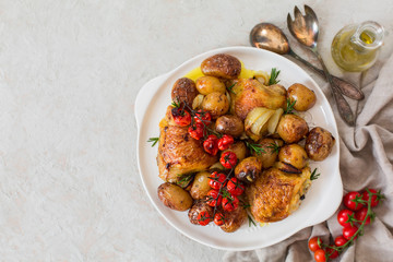 Roasted chicken thighs with baby potatoes, tomatoes, rosemary and onion