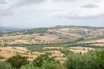 Fototapeta na wymiar Pienza town in distance and Italy Val D'Orcia countryside in Tuscany with hilltop small town village high angle