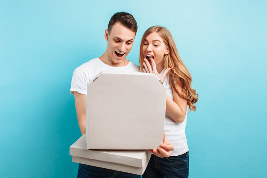 man and woman, hold boxes with Italian pizza, relax on a blue background