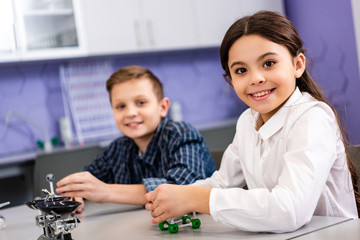 Pupils holding molecule structures while sitting in classroom during chemistry lesson